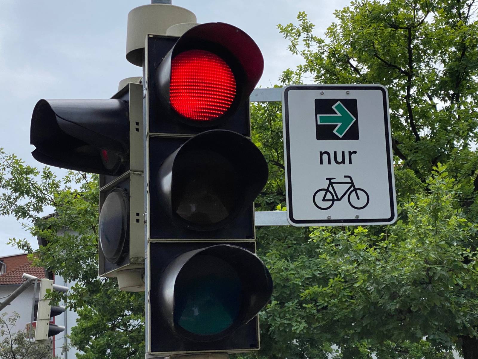 Schild neben einer roten Ampel, das dass Rechtsabbiegen für Radfahrer erlaubt.